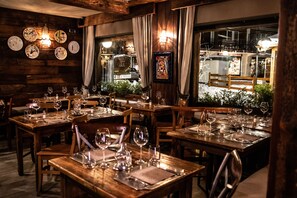 Un restaurant avec des tables et des chaises en bois, des verres à vin et un lustre.