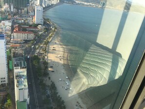 A beach with a view of the ocean and city buildings in the background. - Beach City Apartment (Bac Nha Trang)