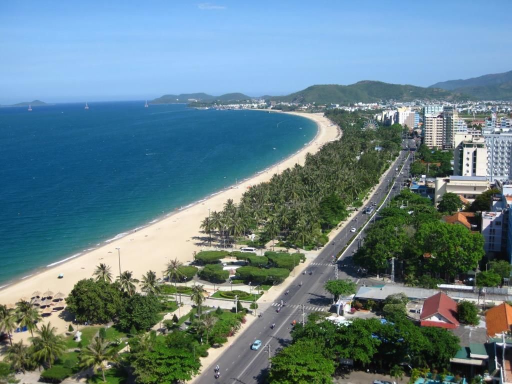 A coastal cityscape with a beach, roads, and buildings.