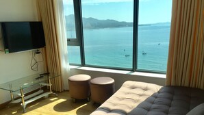A modern room with a large window offering a view of the sea and mountains. - Beach City Apartment (Bac Nha Trang)