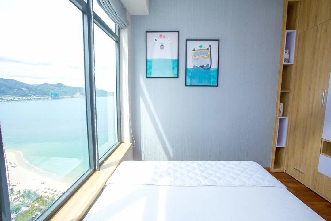 Een slaapkamer met een groot raam, een bed en twee ingelijste foto’s aan de muur.