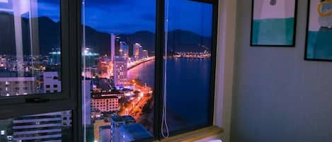 A hotel room with a large window overlooking a cityscape at night.