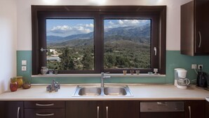 A kitchen with a large window, a sink, and a coffee maker. - Malaxiana Houses (Chania)