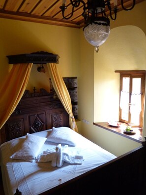 A bedroom with a wooden headboard, a canopy bed, and a window with a view of the outside. - Ta Xelidonakia (South Pelion)
