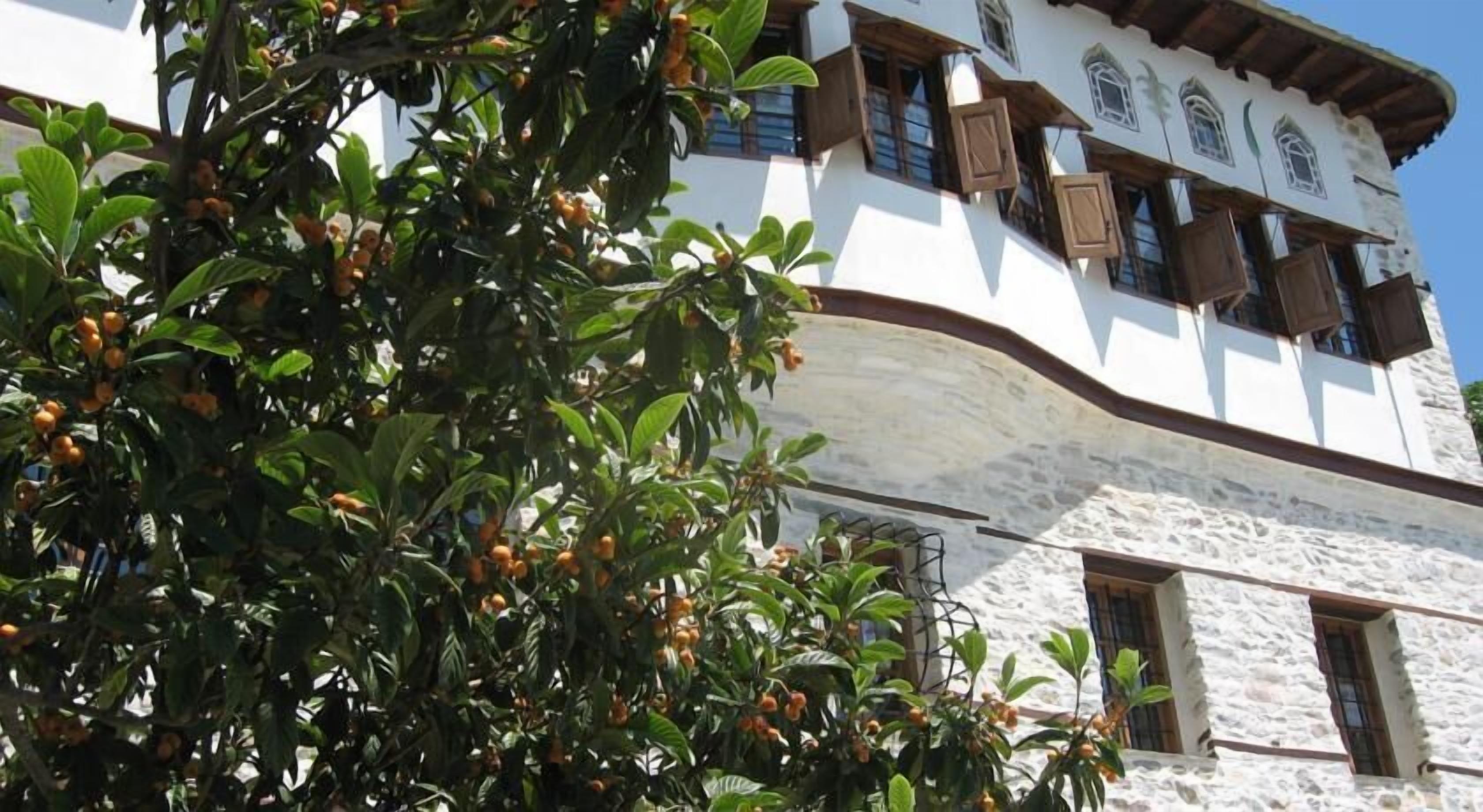 A building with a white facade, wooden shutters, and a stone base.