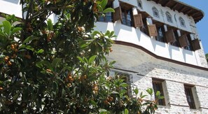 A building with a white facade, wooden shutters, and a stone base. - Ta Xelidonakia (South Pelion)