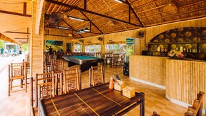 A room with a pool table, chairs, a bar area, and a mural on the wall. - Trang An Valley Bungalow (Tay Hoa Lu)