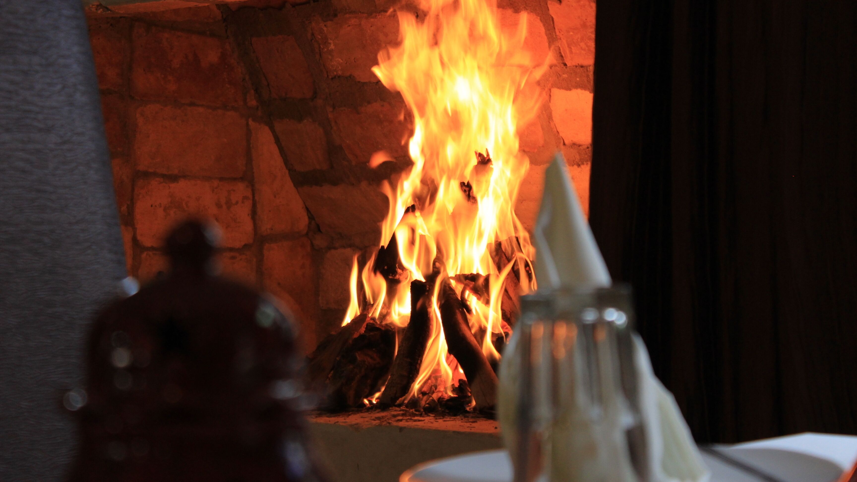 Chimenea con pared de ladrillo y leña ardiendo.