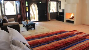 Ein geräumiges Zimmer mit einem großen Bett, einer Couch, einem kleinen Tisch mit Früchten und einem Kamin.