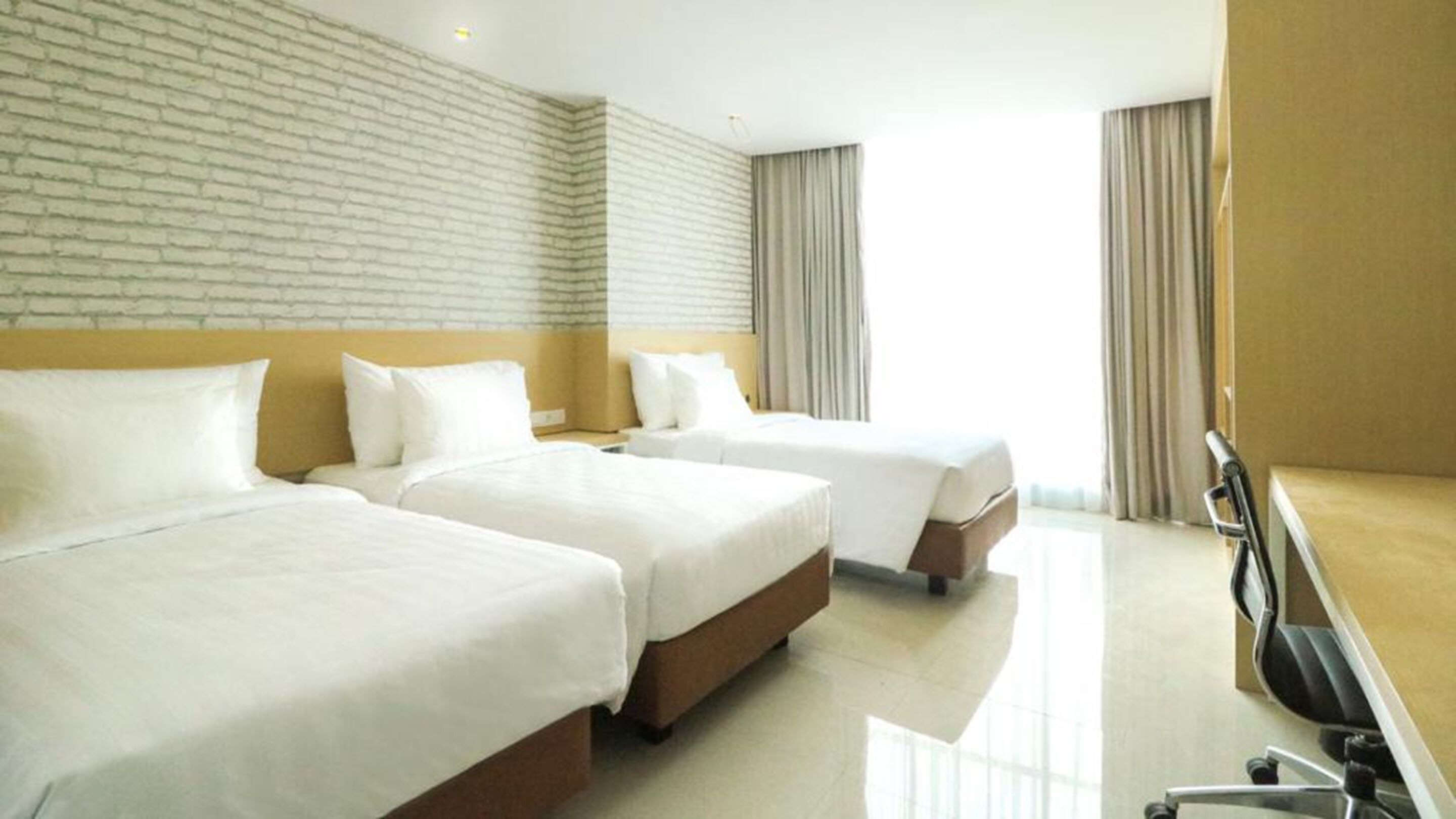 A hotel room with two beds, a desk, and a chair.