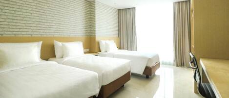 A hotel room with two beds, a desk, and a chair.