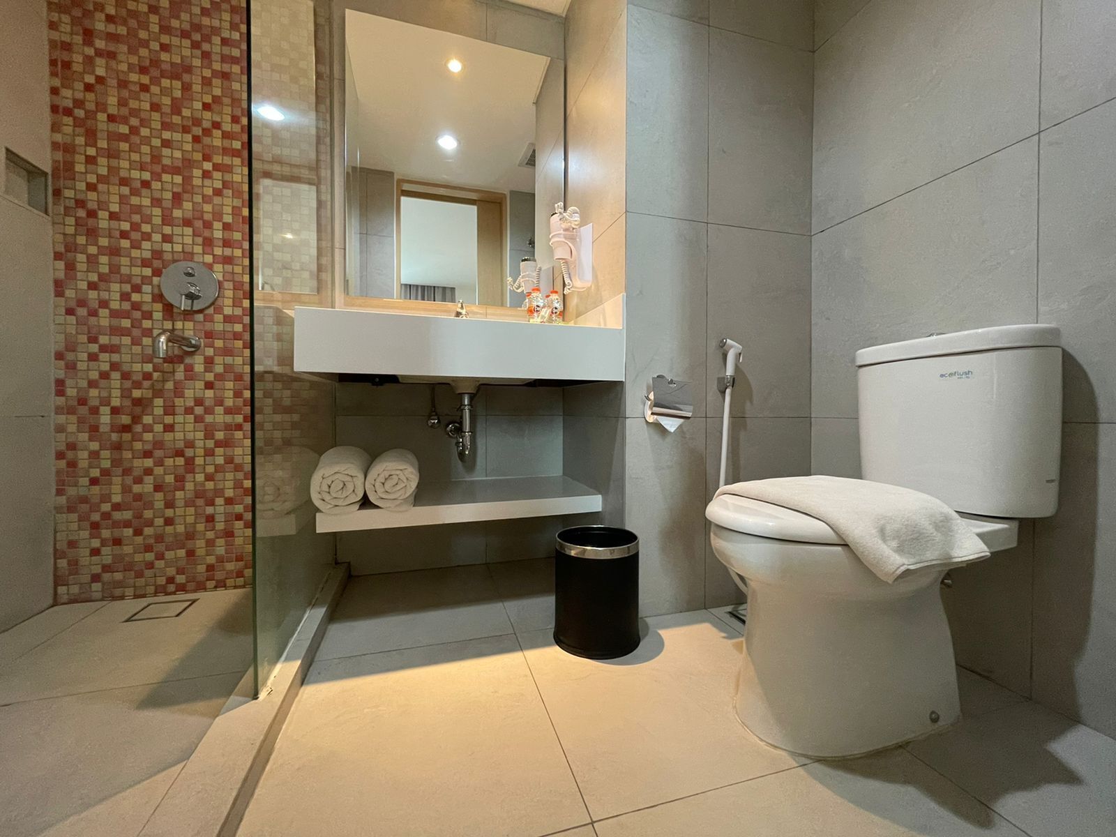Een moderne badkamer met een douchecabine van glas, een wit toilet en een wastafel met spiegel erboven.