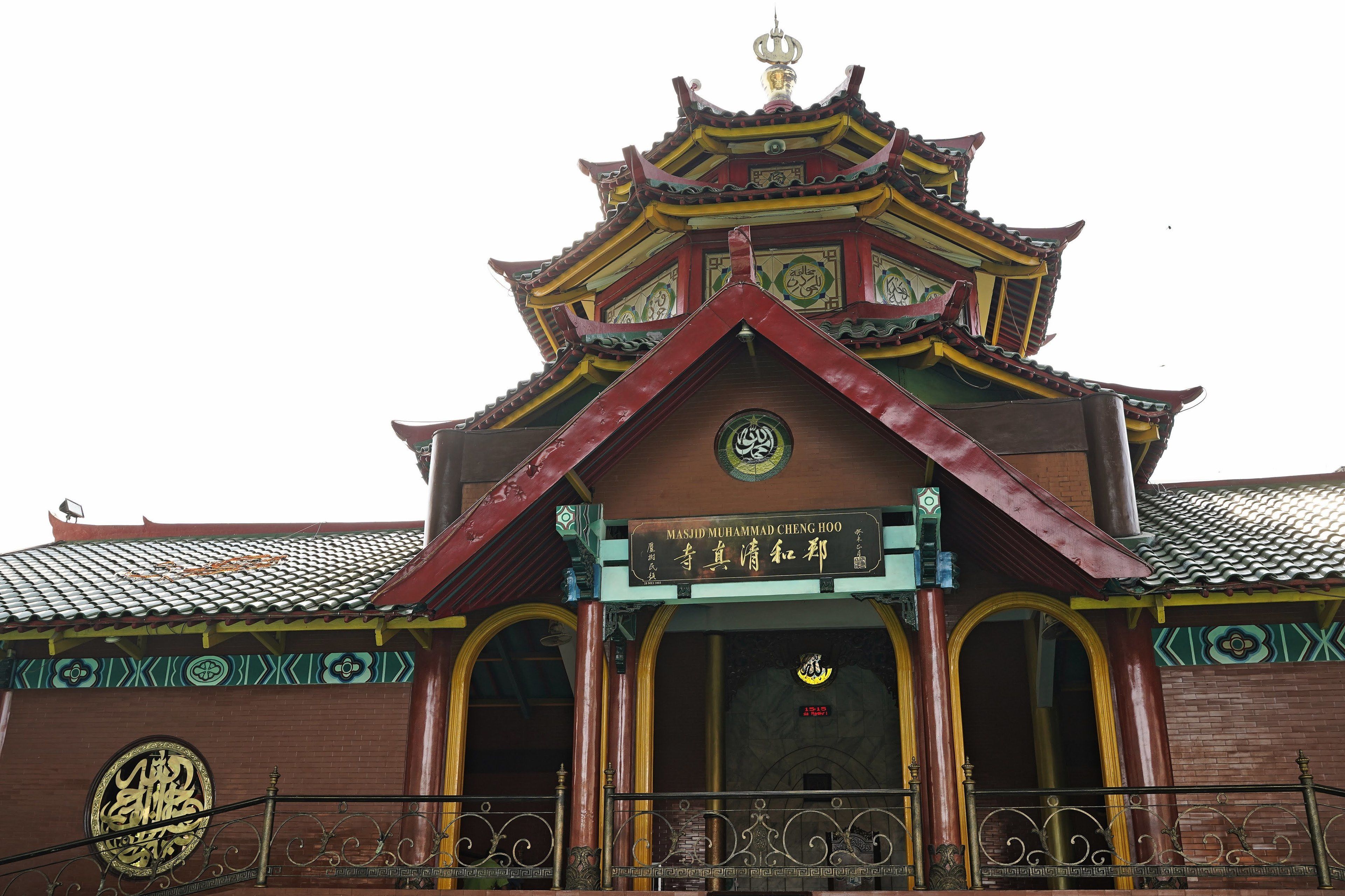 A traditional Chinese building with a multi-tiered roof, a prominent entrance with a sign, and a large circular emblem on the wall.
