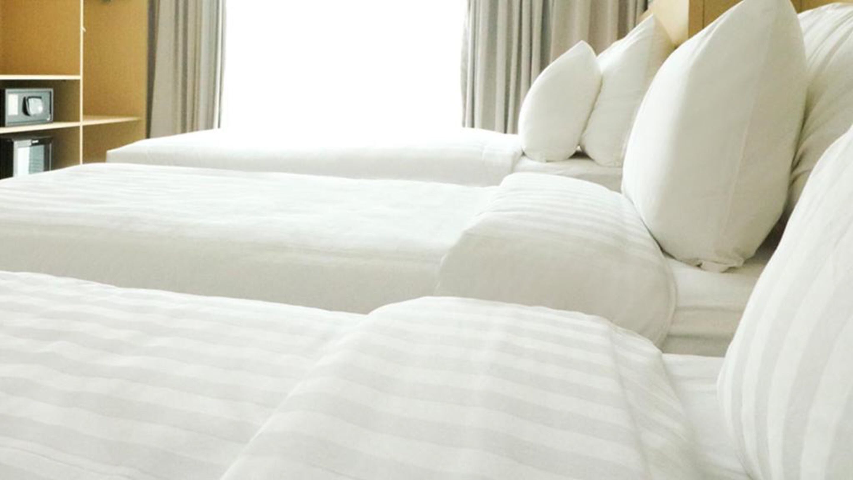 Habitación de hotel con dos camas, cada una con ropa blanca y varias almohadas.