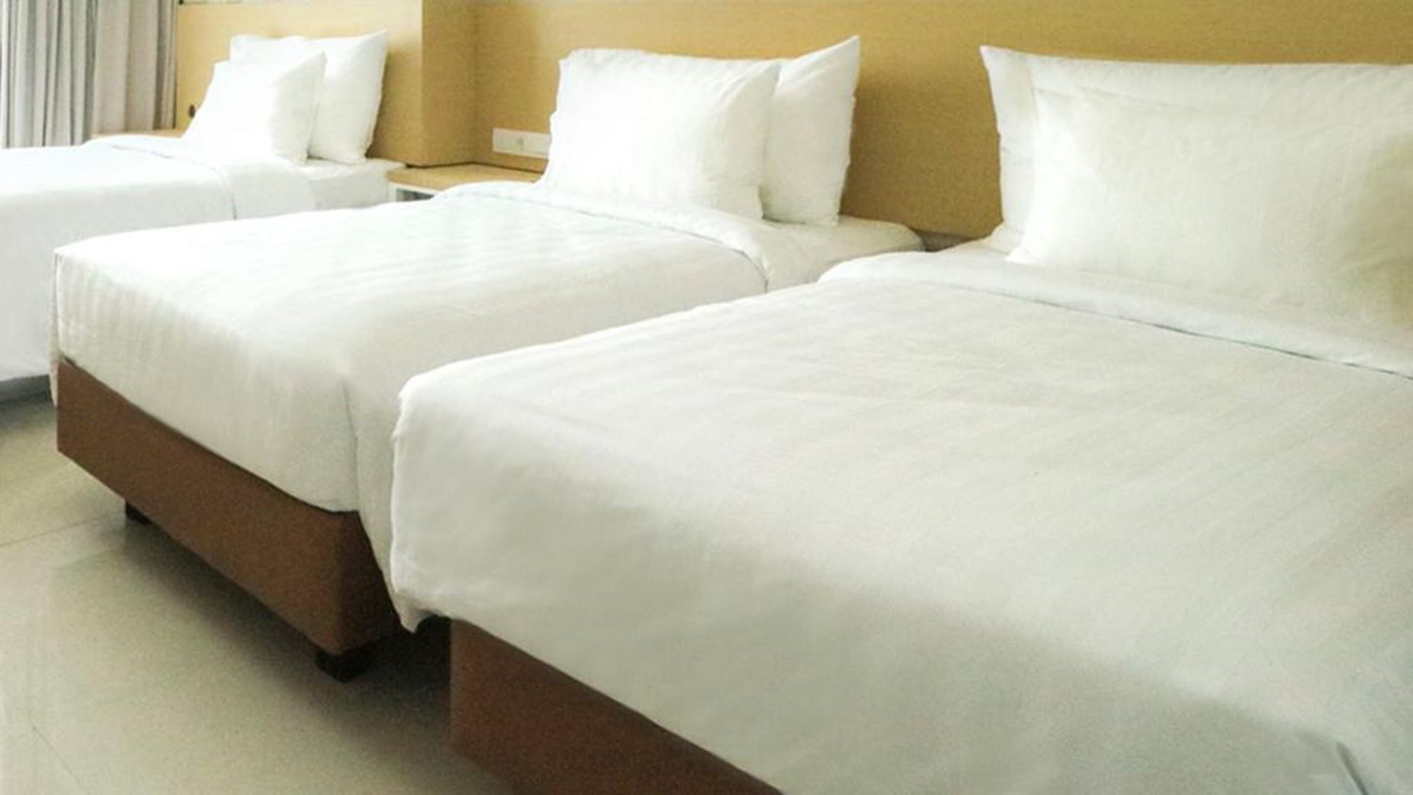 Ein Hotelzimmer mit zwei Betten, jeweils mit weißer Bettwäsche und einem Holzkopfstück.