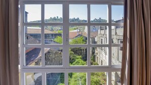 A window with a view of buildings and greenery. - A Morada do Cigarron (Verín)
