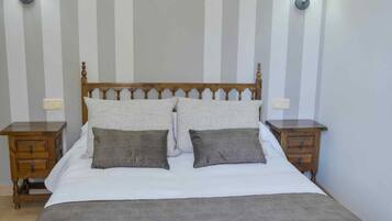 A bedroom with a wooden bed, two bedside tables, and striped wallpaper.