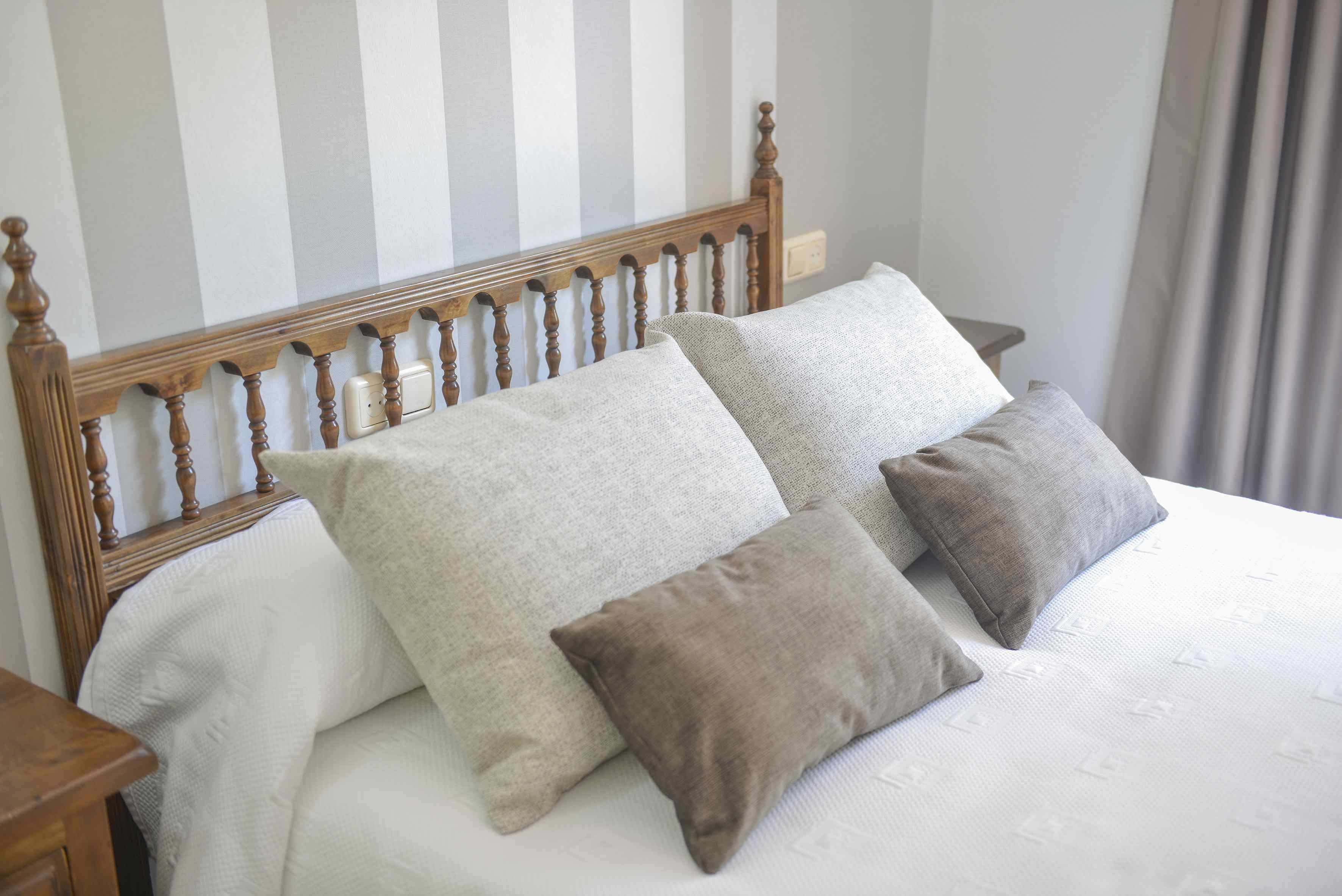 A bed with a wooden headboard, two pillows, and a white bedspread.