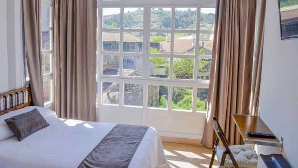 A bedroom with a large window, a bed, a desk, and a chair. - A Morada do Cigarron (Verín)