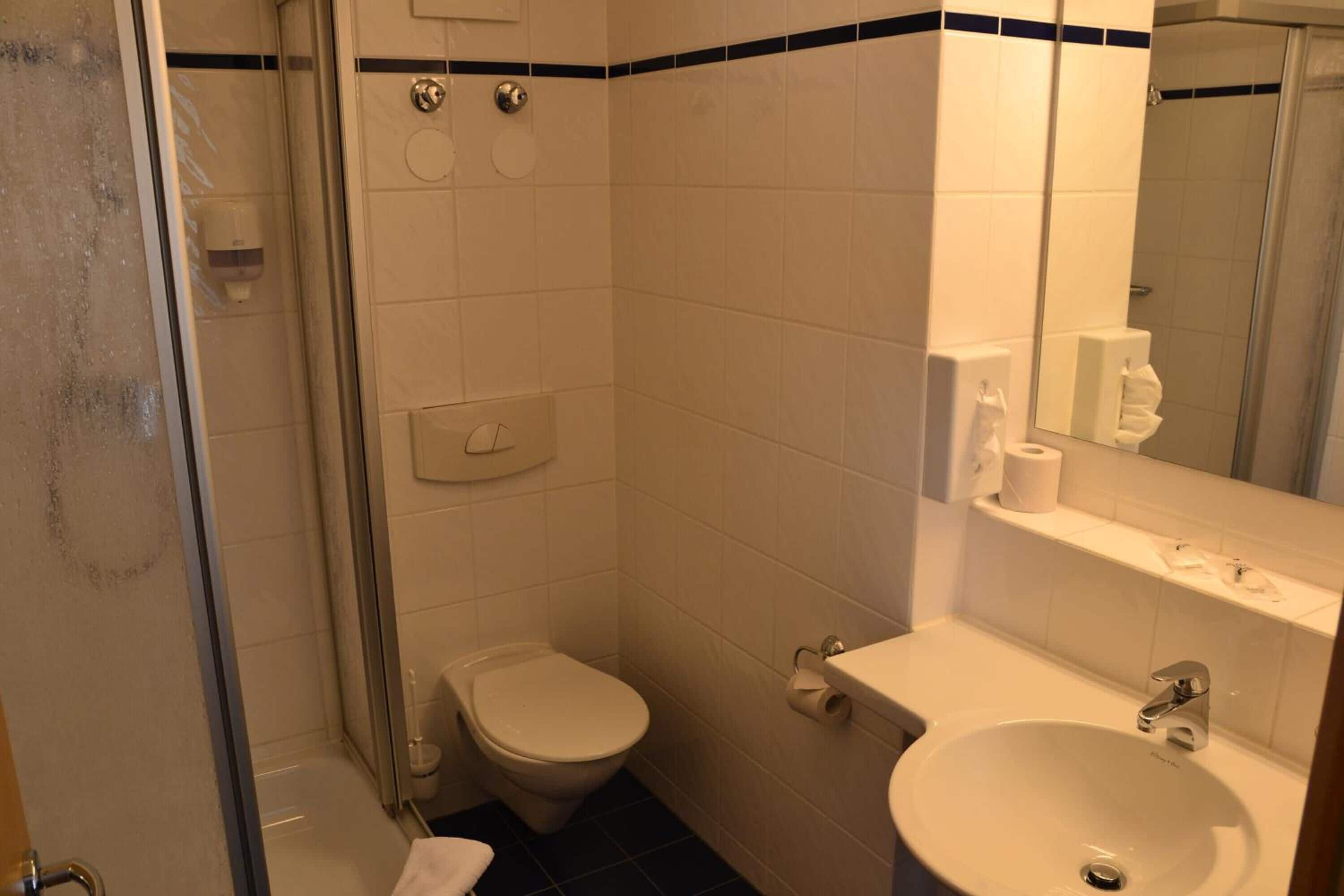 Een badkamer met toilet, wastafel en douche.