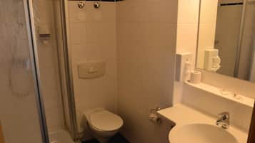 Een badkamer met toilet, wastafel en douche.