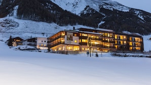 A multi-story hotel with a restaurant and bar, surrounded by snow-covered mountains. - Langtauferer Hof (Curon Venosta)