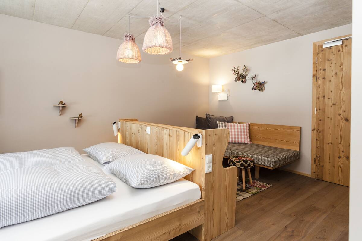 A cozy bedroom with two wooden beds, a wooden wardrobe, and a small table.