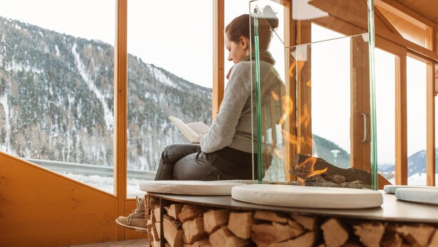 A person sitting by a window with a view of a snowy mountain, reading a book. - Langtauferer Hof (Curon Venosta)