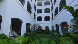 A multi-level courtyard with white walls, arched doorways, and a central staircase. - Alpha Old Court House (Kochi)