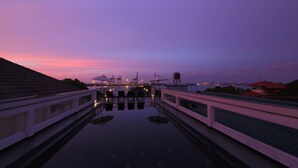 A waterfront promenade with a reflective pool, railings, and distant industrial structures. - Alpha Old Court House (Kochi)