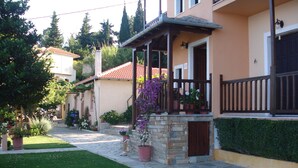 A residential building with a stone facade, a balcony with a wooden railing, and a well-maintained garden. - Alkmini (Zagora-Mouresi)