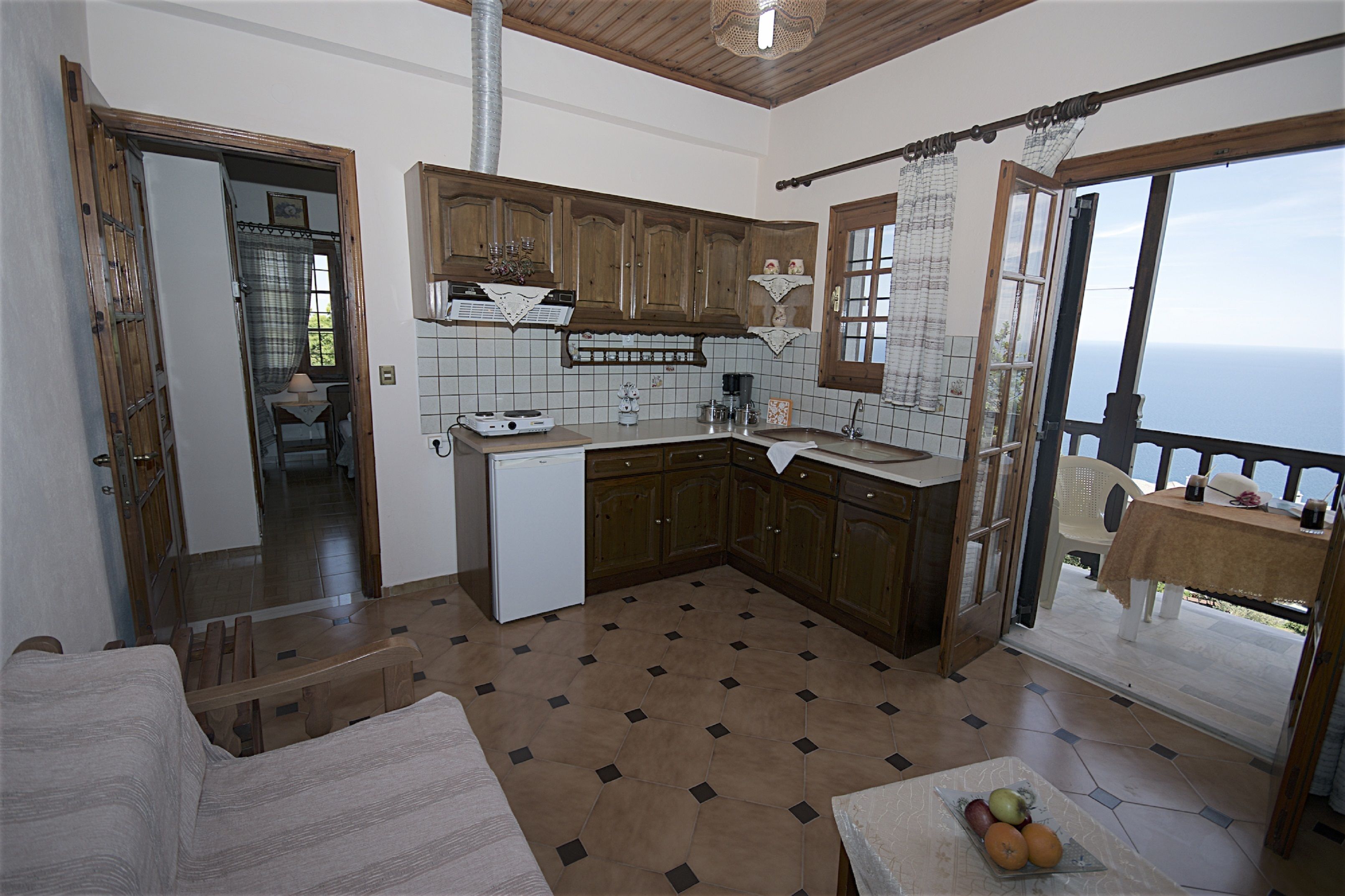 A kitchen with wooden cabinets, a refrigerator, and a dining area with a table and chairs.