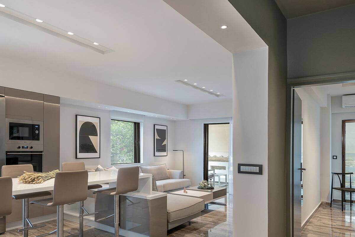 A modern living room with a dining area, a sofa, and a kitchen with built-in appliances.