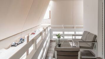 A balcony with a white railing, a sofa, a small table, and a potted plant.