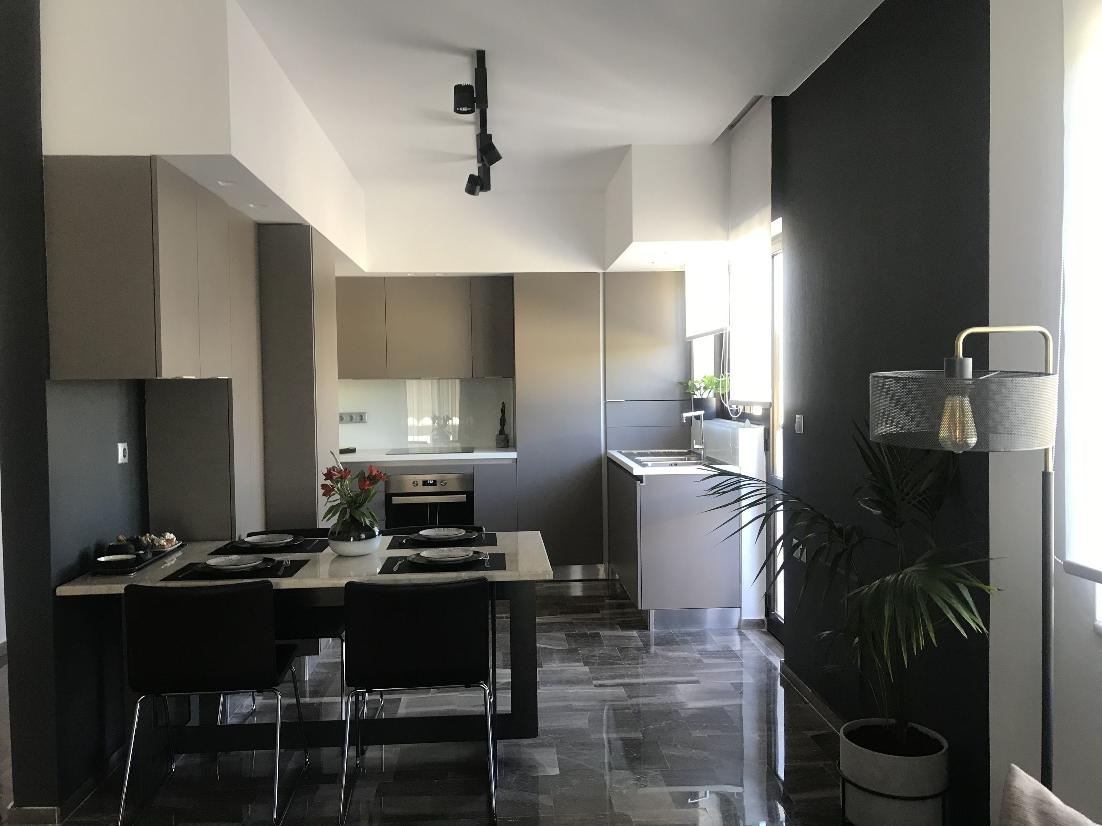 A modern kitchen with a dining area, featuring a central island, dark flooring, and a view into the adjacent dining room.