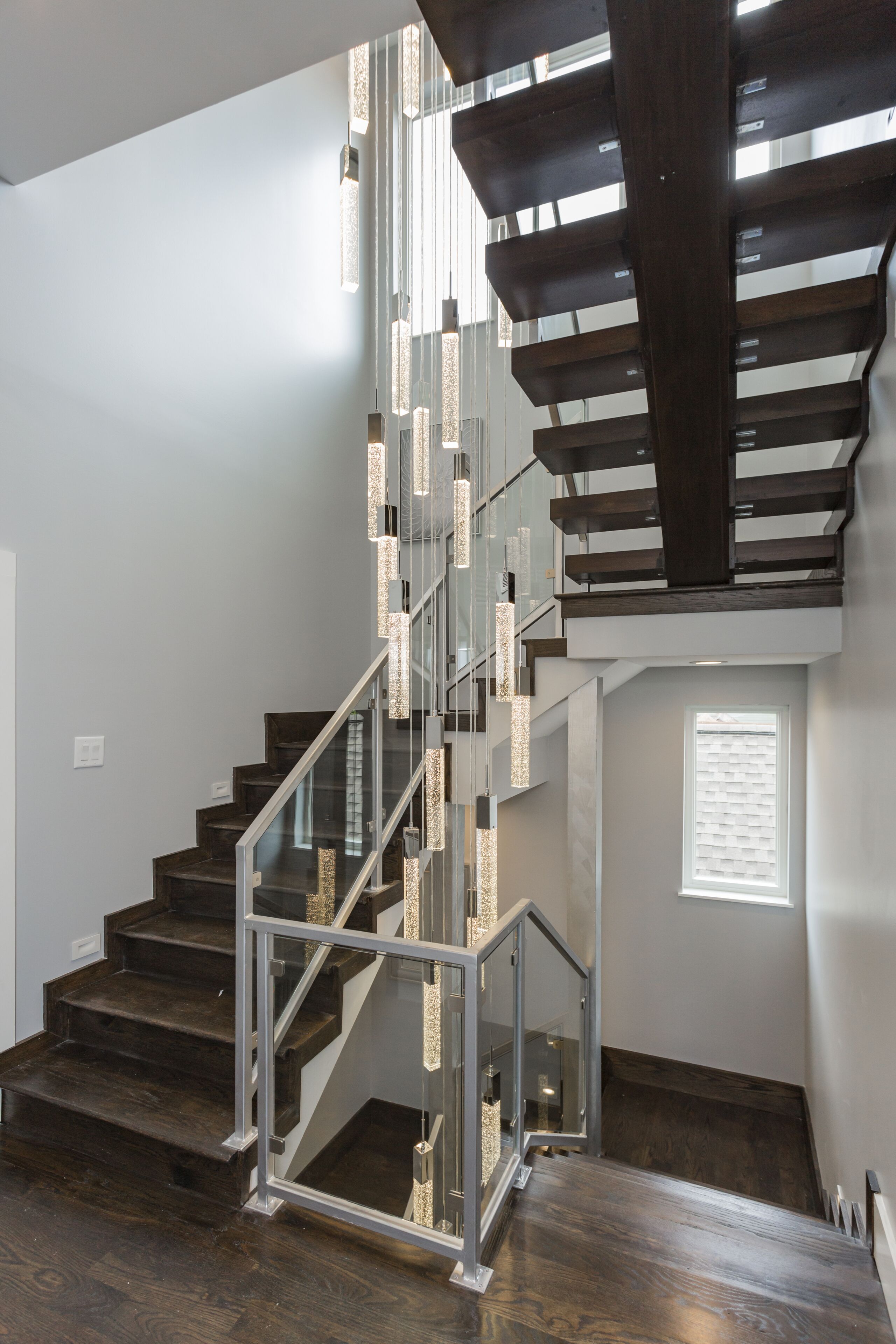 Una escalera moderna con barandillas de vidrio y peldaños de madera.