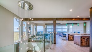 A modern kitchen with a large island, glass railings, and a view of the outdoors.