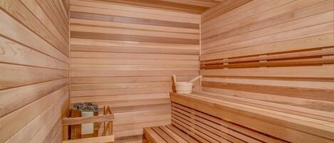 A wooden sauna with benches and a small shelf with a bucket and brush.