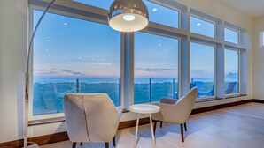 A spacious room with large windows, a modern chandelier, and two chairs facing the view.