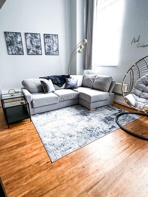 Relax in this stylish living room with a grey sofa, coffee table, and side table, surrounded by a large rug and abstract artwork.