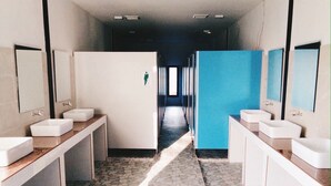 Un baño público con dos lavamanos, un espejo y piso de baldosas.