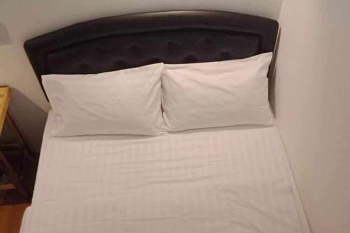 A bed with a black headboard and two white pillows.