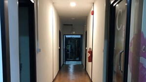 Un pasillo con suelo de madera, puertas de cristal y un extintor en la pared.