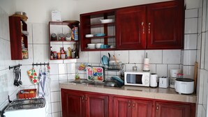 Una cocina con armarios de madera, estufa a gas, microondas y varios utensilios de cocina.