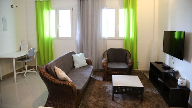 Una sala de estar con sofá, sillón, mesa de centro, televisor y escritorio con silla.