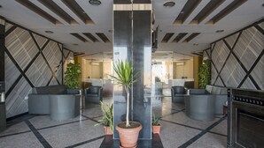 En moderne lobby med en central søjle, siddepladser og plantekasser.