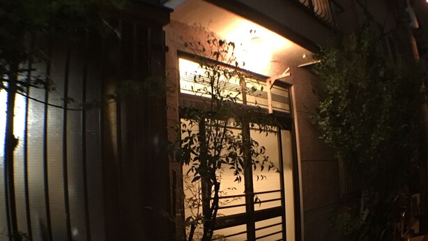 A building with a large glass door, a small balcony, and a bicycle parked outside. - Ryokan Nakadaya (Tokyo)