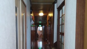 A long, narrow hallway with wooden flooring and white walls. - Ryokan Nakadaya (Tokyo)