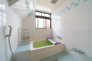 A bathroom with a bathtub, a window, and a shower.