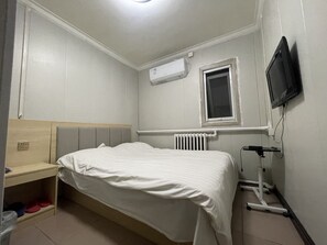 A bedroom with a bed, a window, an air conditioner, a TV, and a radiator. - Beijing Huairou Pan Jia Yuan Hotel (Huairou)